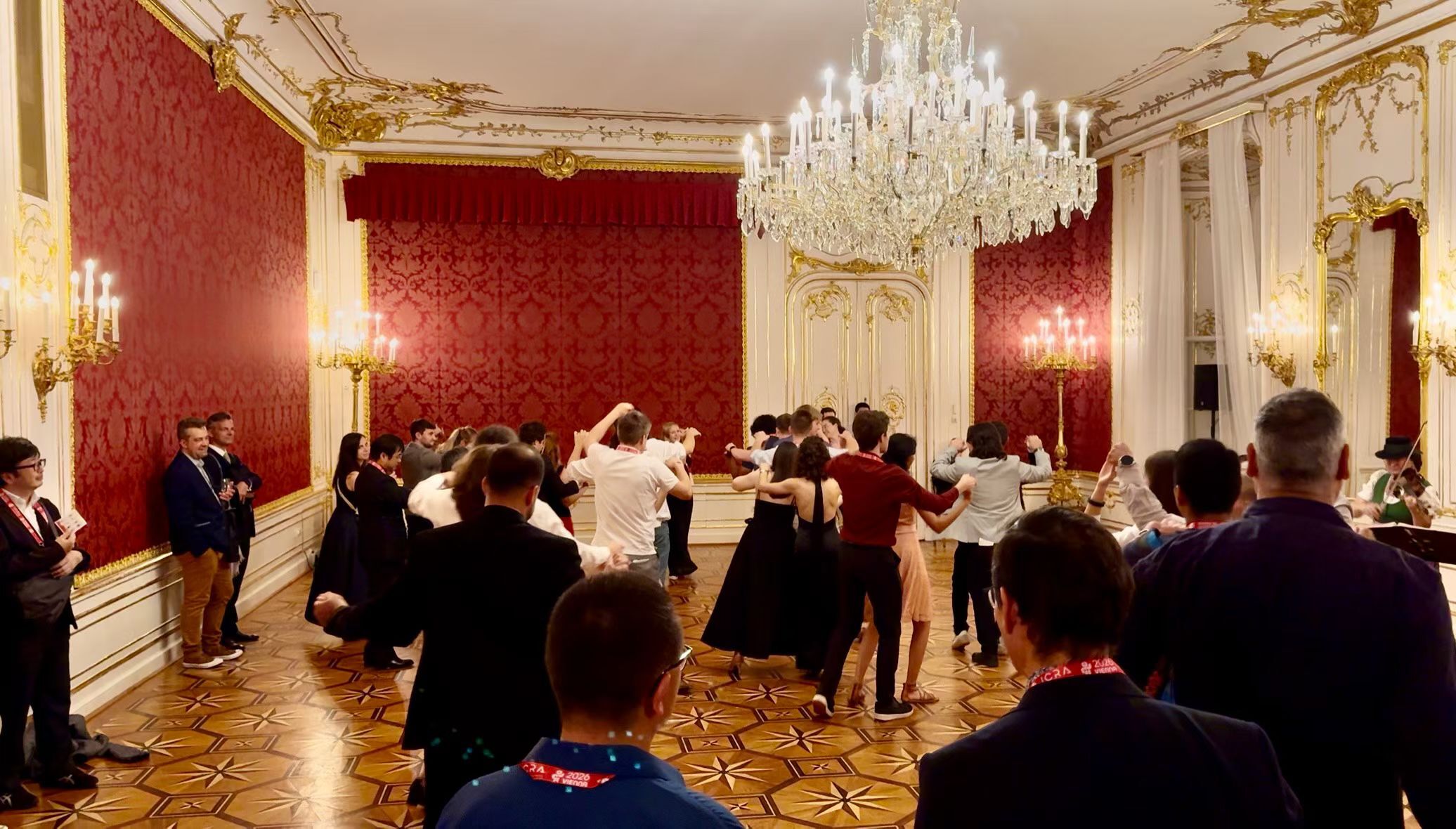 Conference attendees dancing together in an ornate room at the Hofburg