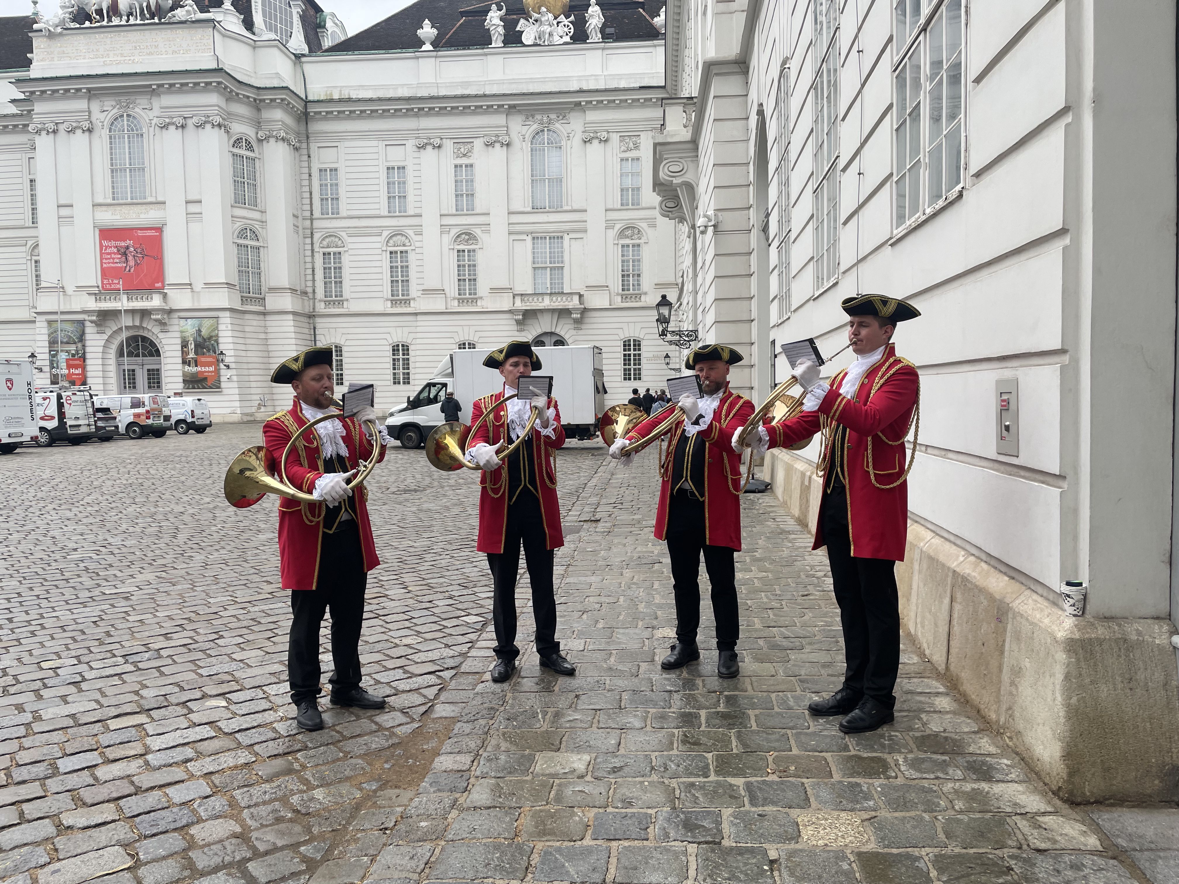 Musicians in red historical dress performing outside the Hofburg Palace
