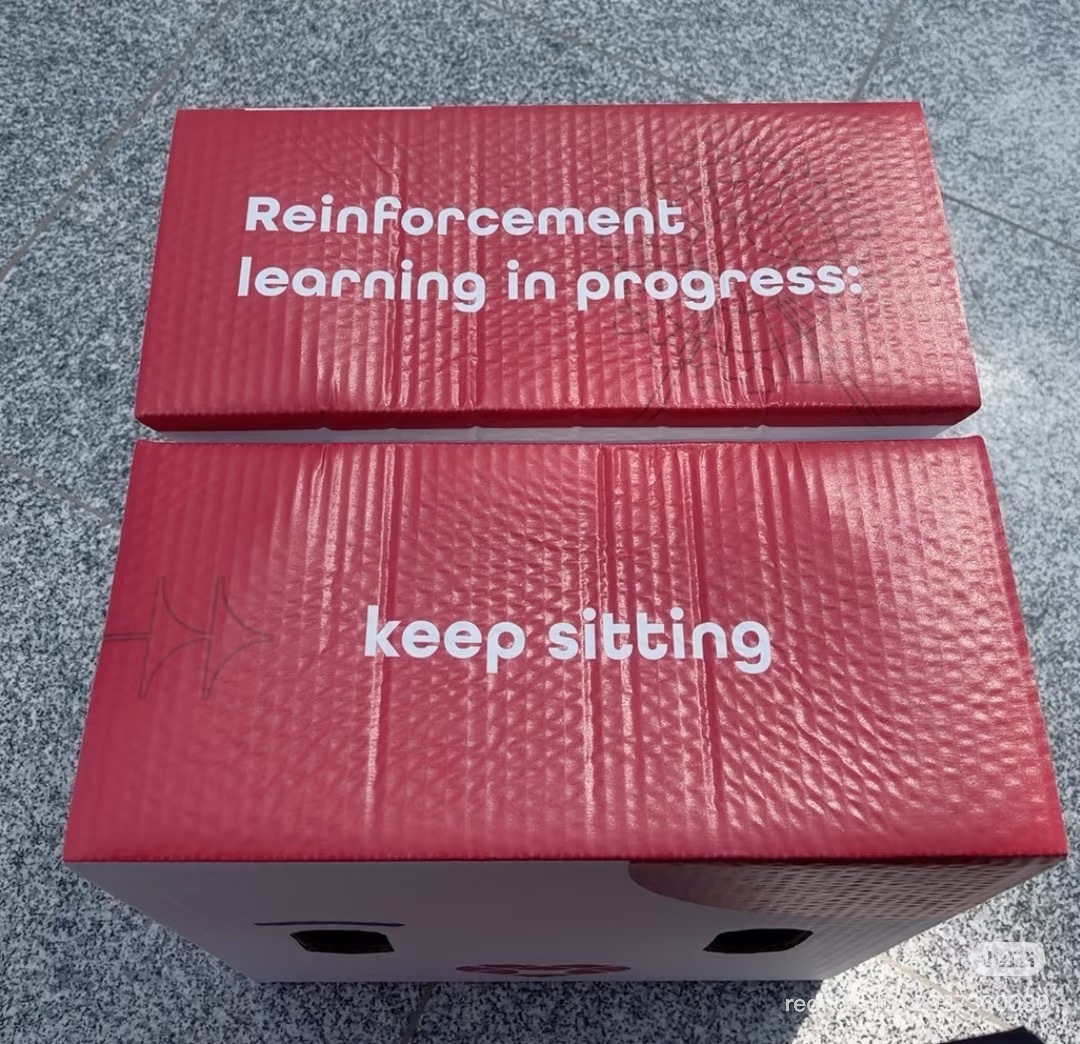 Red cardboard seats printed with Reinforcement learning in progress and keep sitting
