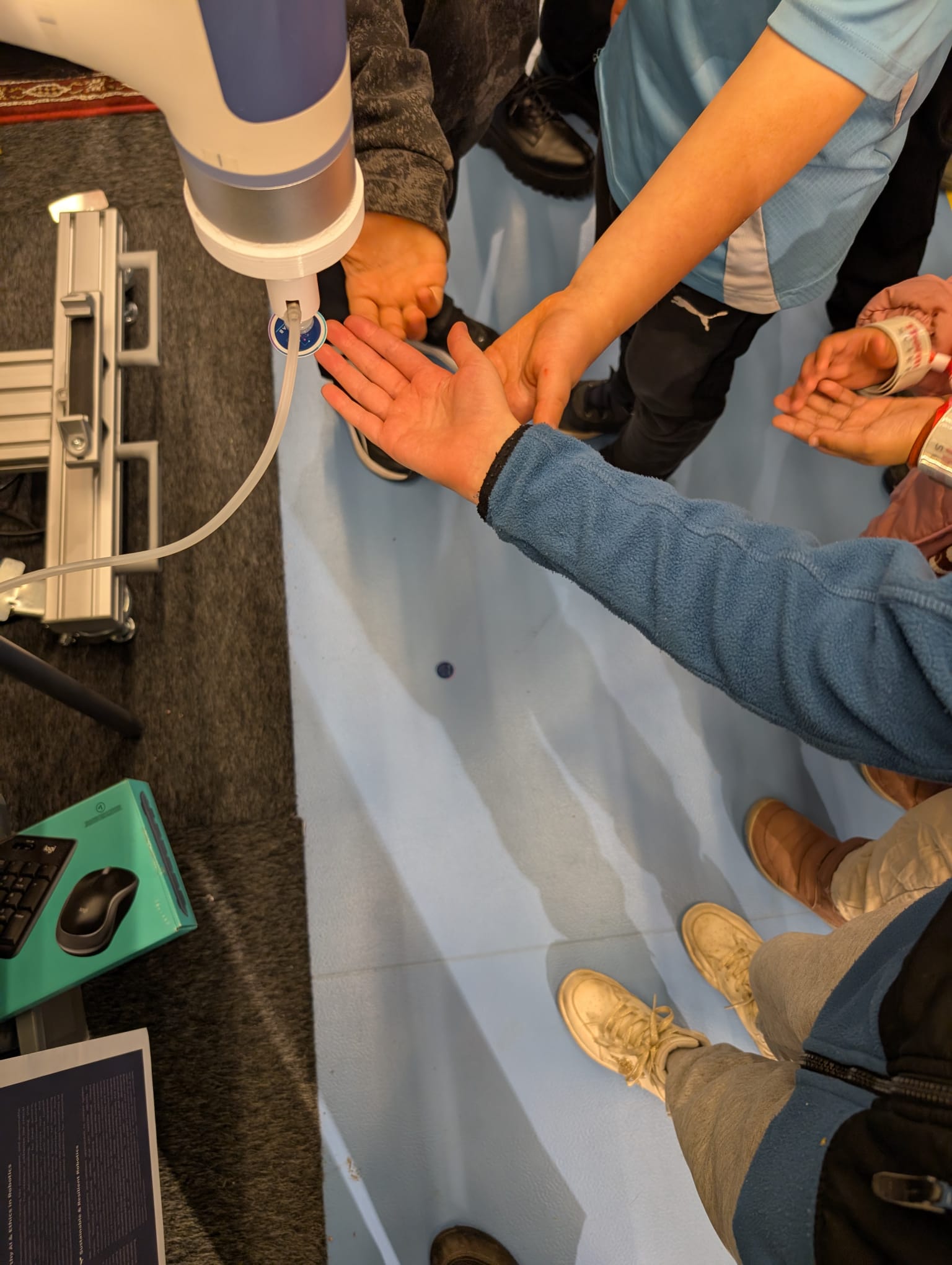 Hands waiting to receive a sticker from the
                                                                                                robotic arm